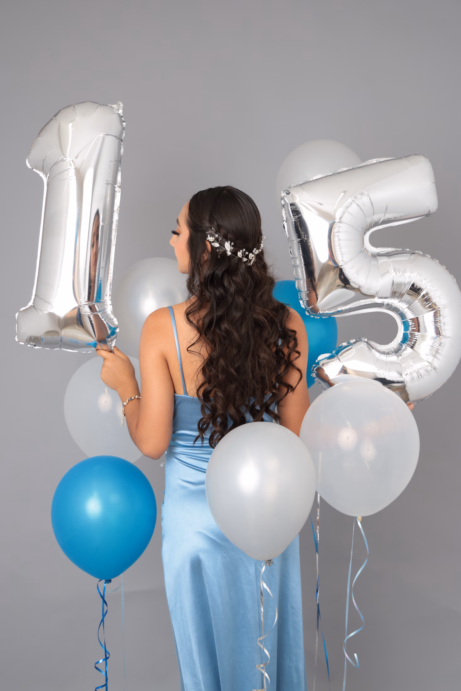 Vista posterior de quinceañera con globos de número 15