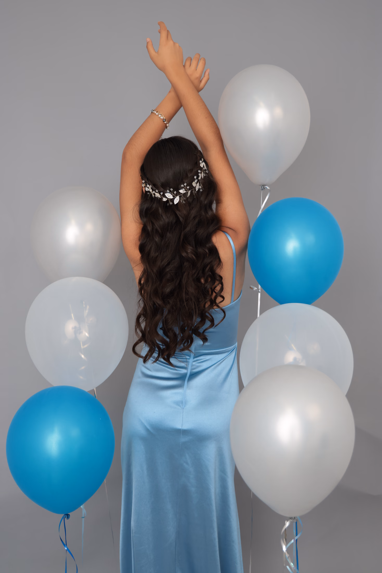Quinceañera de espaldas con tocado floral y globos