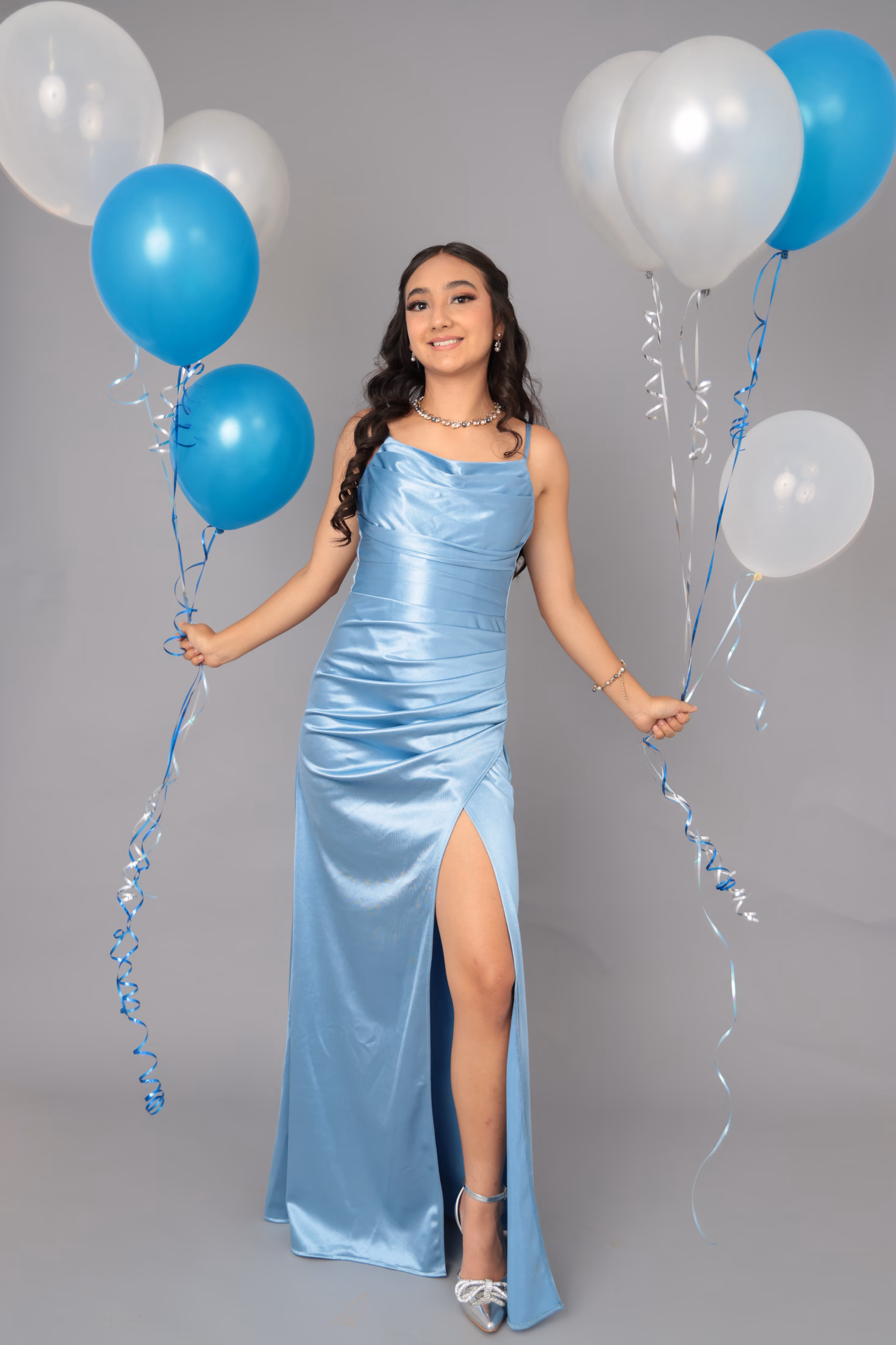 Quinceañera con vestido azul satinado y globos festivos
